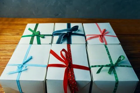 Stack of white gift boxes with ribbons on wooden table. Stock Photos