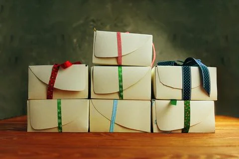 Stack of white gift boxes with ribbons on wooden table. Stock Photos