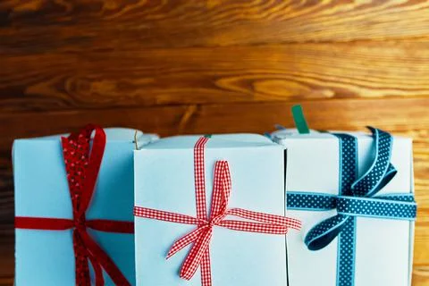 Stack of white gift boxes with ribbons on wooden table. Stock Photos