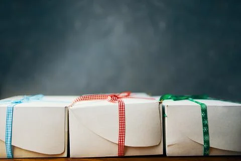 Stack of white gift boxes with ribbons on wooden table. Stock Photos