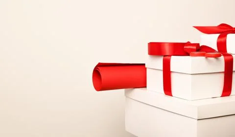 Stack of white gifts with red bows and red wrapping paper against white backg Stock Photos