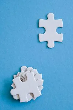 Stack of white jigsaw pieces to be placed onn blue board with single piece Stock Photos