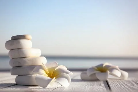 Stack of white marble stones and beautiful flower on wooden deck, space for t 写真素材