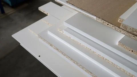A stack of white MDF panels lies on the floor. Material for the production .. Stock Photos