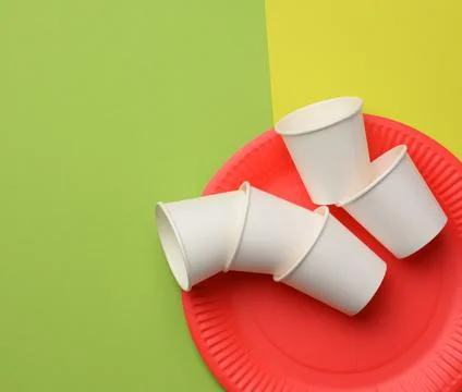 Stack of white paper cups and red round plates on a green background. Foto stock
