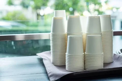 Stack of white paper cups on a table near window Stock Photos