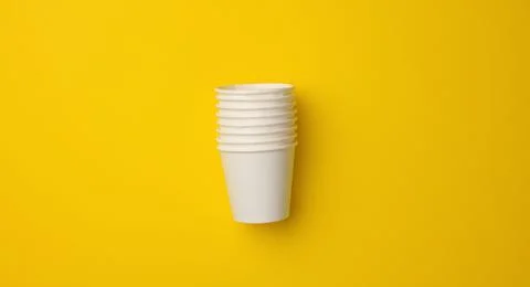 Stack of white paper cups on a yellow background. Plastic rejection concept,  库存照片