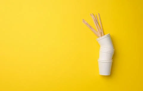 Stack of white paper cups on a yellow background. Plastic rejection concept,  Stock Photos
