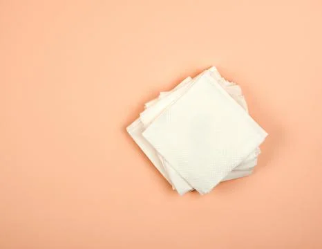 Stack of white paper napkins on a beige background, top view 写真素材
