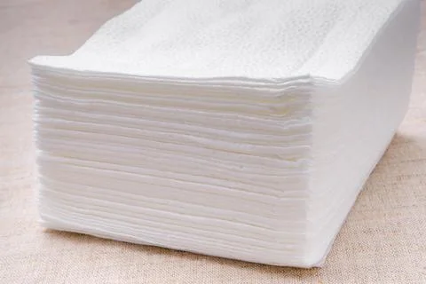 A stack of white paper napkins on a light-colored tablecloth. Stock Photos