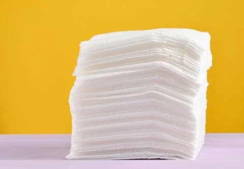 A stack of white paper napkins on a yellow pastel background.. A stack of whi 库存照片