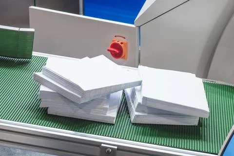 Stack of white papers is on a conveyor belt. The conveyor belt is green and t Foto stock