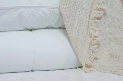 Stack of white pillows and blankets lies on the bed on a white sheet on top Stock Photos