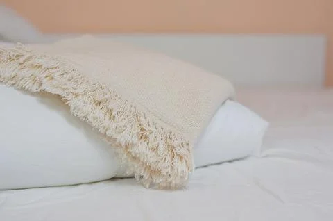 Stack of white pillows and blankets lies on the bed on a white sheet on top Stock Photos