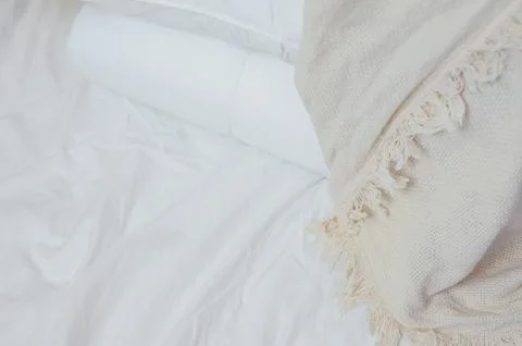 Stack of white pillows and blankets lies on the bed on a white sheet on top Stock Photos