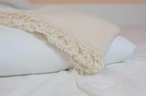 Stack of white pillows and blankets lies on the bed on a white sheet on top Stock Photos