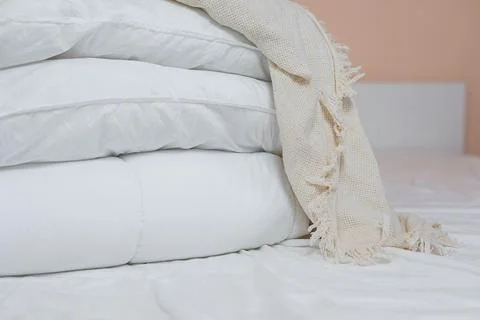 Stack of white pillows and blankets lies on the bed on a white sheet on top Stock Photos
