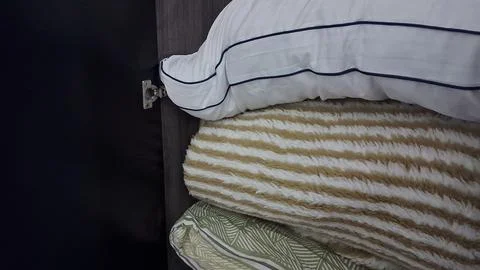 Stack of white pillows and striped blankets inside wooden storage closet Stock Photos