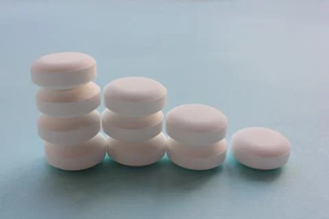 Stack of white pills on blue background. Graphic made from pills. Stock Photos