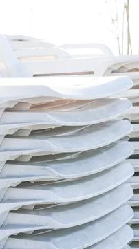 A stack of white plastic sun loungers or beach chairs Stock Photos
