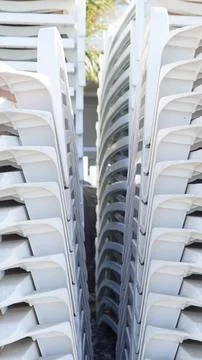 A stack of white plastic sun loungers or beach chairs Stock Photos