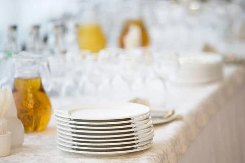  A stack of white plates on the table with a carafe of juice plastic cups ... Stock Photos