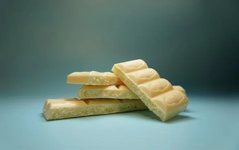 Stack of white porous chocolate bars with creamy texture on gradient blue Foto stock