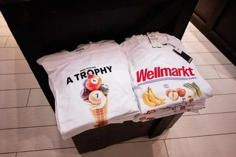 Stack of white printed t-shirts on a wooden table in a retail store Foto stock