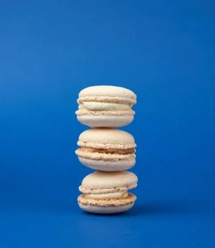 Stack of white round baked almond flour cakes macarons on a dark blue backgro Stock Photos