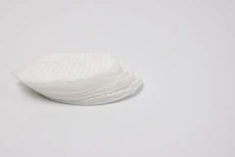 Stack of white round cotton pads on plain light background with negative spac Stock Photos