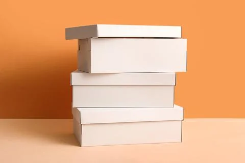 Stack of white shoeboxes on orange background Fotos de archivo