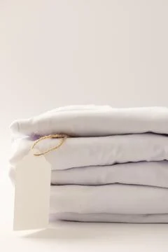 Stack of white t shirts with tag and copy space on white background Stock Illustration