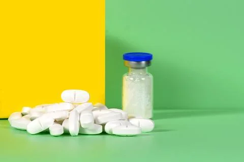 Stack of white tablets and medical vial Medicinal powder for saline injection Stock Photos