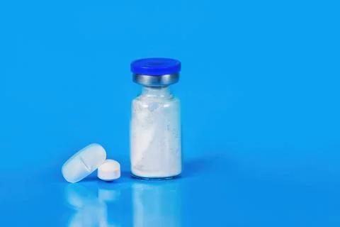Stack of white tablets and medical vial Medicinal powder for saline injection Stock Photos