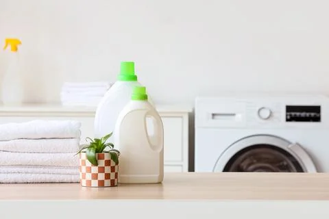 Stack of white towels with laundry detergents and plant on table in room Stock Photos
