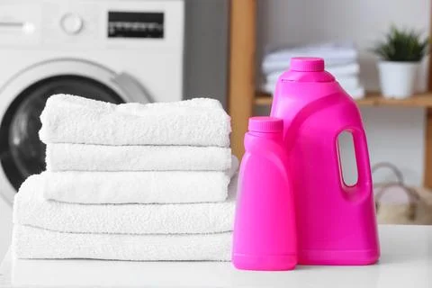 Stack of white towels with laundry detergents on table in room Stock Photos