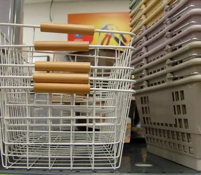 Stack of white wire baskets with wooden handles sits prominently on a store.. Stock Photos