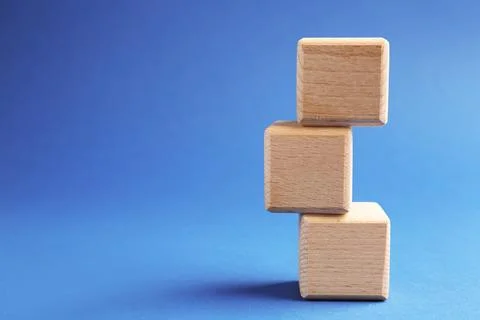 Stack of wooden cubes on blue background, closeup. Space for text Stockfoto's