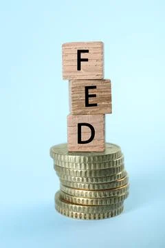 Stack of wooden cubes with letters Fed (Federal Reserve System) and coins o.. 스톡 사진