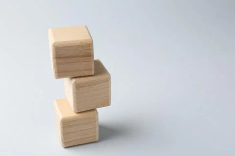 Stack of wooden cubes on light grey background, closeup. Space for text Stockfoto's