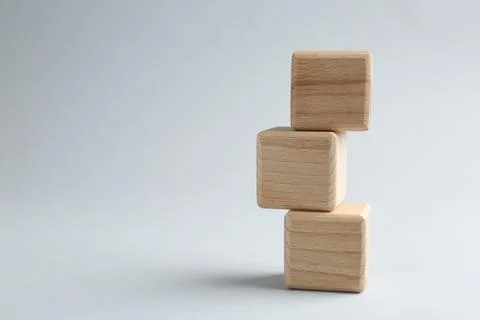 Stack of wooden cubes on light grey background, closeup. Space for text Stockfoto's