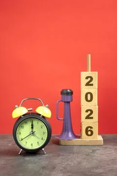 Stack of wooden cubes with the number 2026 with an alarm clock and plastic .. Fotos de archivo