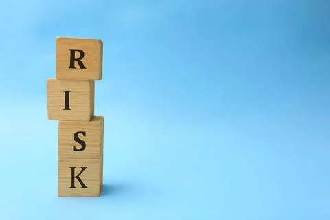 Stack of wooden cubes with word Risk on light blue background. Space for text 스톡 사진