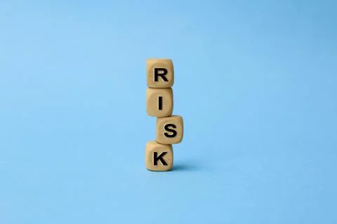 Stack of wooden cubes with word Risk on light blue background Stockfoto's