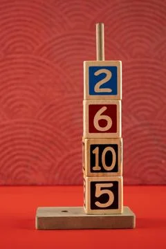 Stack of wooden number blocks with various numbers on a red background Stock Photos