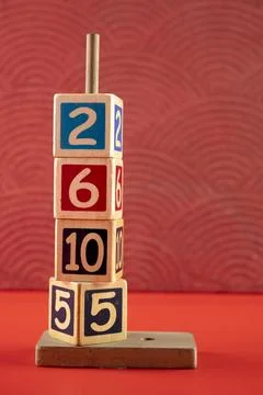 Stack of wooden number blocks with various numbers on a red background Stock Photos