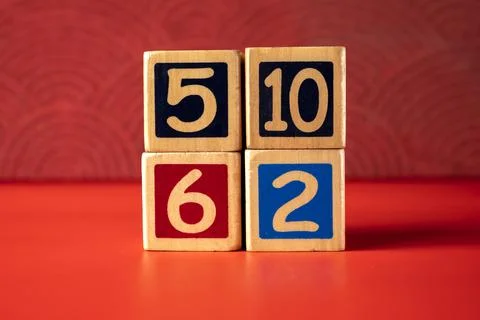 Stack of wooden number blocks with various numbers on a red background Stock Photos