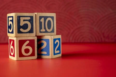 Stack of wooden number blocks with various numbers on a red background Stock Photos