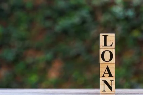 Stack wooden square block with L O A N text on wood table with space at left. Stock Photos