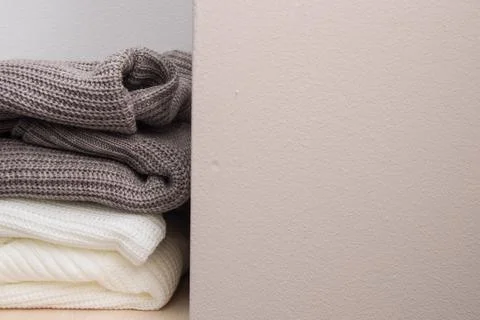 A stack of wool sweaters on the shelf. Grey and white sweater. Warm and cozy. Stock Photos